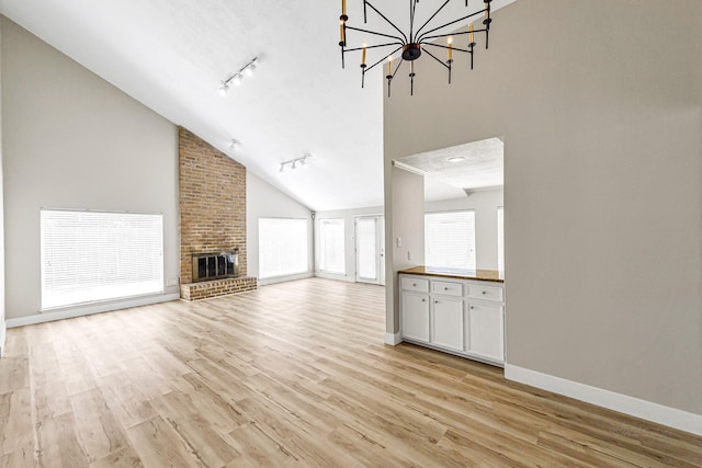 12014 Briar Forest Dr, Houston, TX 77077 - unfurnished living room with rail lighting, light wood-style floors, baseboards, a chandelier, and high vaulted ceiling