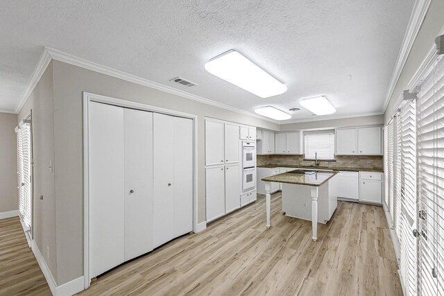 12014 Briar Forest Dr, Houston, TX 77077 - kitchen with light wood finished floors, ornamental molding, white appliances, white cabinets, and a kitchen bar