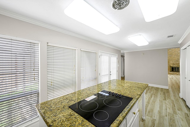 12014 Briar Forest Dr, Houston, TX 77077 - kitchen with black electric stovetop, crown molding, light wood-type flooring, white cabinets, and stone counters