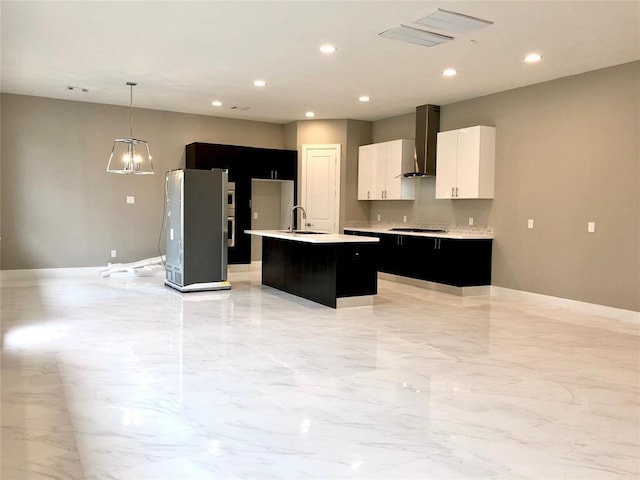 1920 Pueblo Nuevo Path, Houston, TX 77077 - kitchen with wall chimney exhaust hood, a kitchen island with sink, dark cabinetry, light countertops, and light marble finish floors