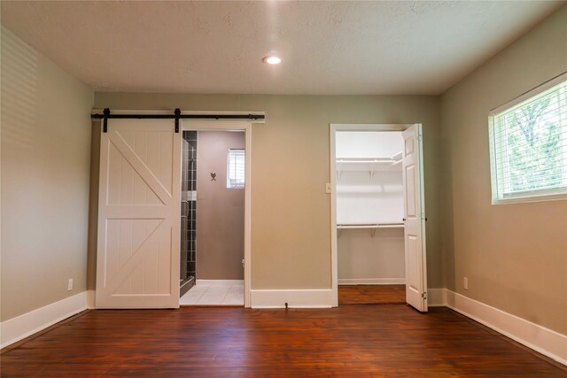4801 Walker St, Houston, TX 77023 - unfurnished bedroom with wood finished floors, a barn door, baseboards, and recessed lighting