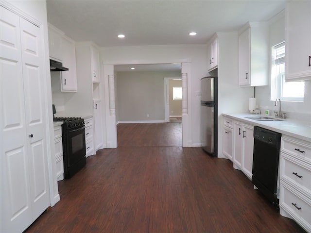 4801 Walker St, Houston, TX 77023 - kitchen featuring black appliances, a sink, under cabinet range hood, dark wood finished floors, and light countertops
