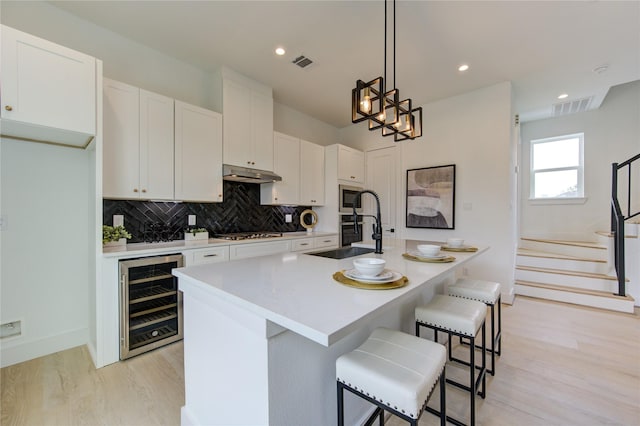 2312 Reinerman St, Houston, TX 77007 - kitchen featuring wine cooler, a sink, gas cooktop, light wood-style flooring, and tasteful backsplash