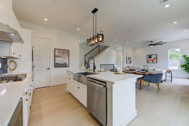 2312 Reinerman St, Houston, TX 77007 - kitchen featuring appliances with stainless steel finishes, a sink, light wood-type flooring, a center island with sink, and white cabinetry