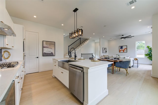 2312 Reinerman St, Houston, TX 77007 - kitchen featuring appliances with stainless steel finishes, light wood finished floors, a sink, white cabinets, and an island with sink