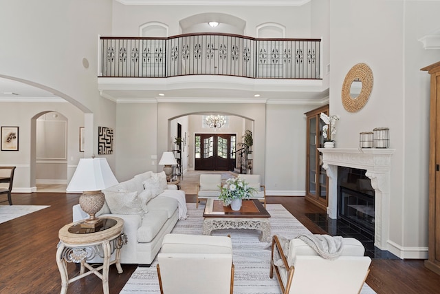 26 Commanders Pt, Missouri City, TX 77459 - living room featuring a high ceiling, arched walkways, baseboards, wood finished floors, and a fireplace with flush hearth