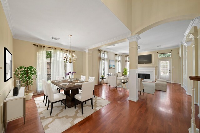 1123 Mariner Cv, Sugar Land, TX 77498 - dining room featuring ornate columns, wood finished floors, a fireplace, arched walkways, and ornamental molding