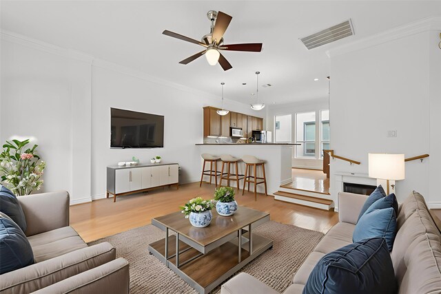 5731 Kansas St, Houston, TX 77007 - living room with ceiling fan, light wood finished floors, crown molding, and recessed lighting
