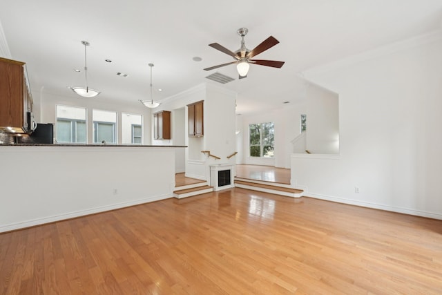 5731 Kansas St, Houston, TX 77007 - unfurnished living room featuring light wood-style flooring, baseboards, ceiling fan, and ornamental molding