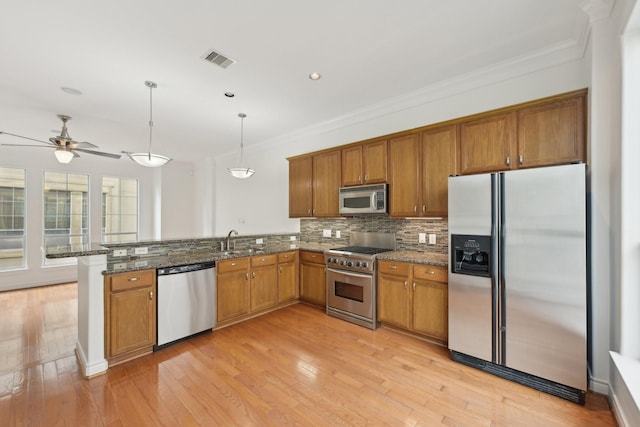 5731 Kansas St, Houston, TX 77007 - kitchen featuring stainless steel appliances, brown cabinetry, a peninsula, crown molding, and a sink