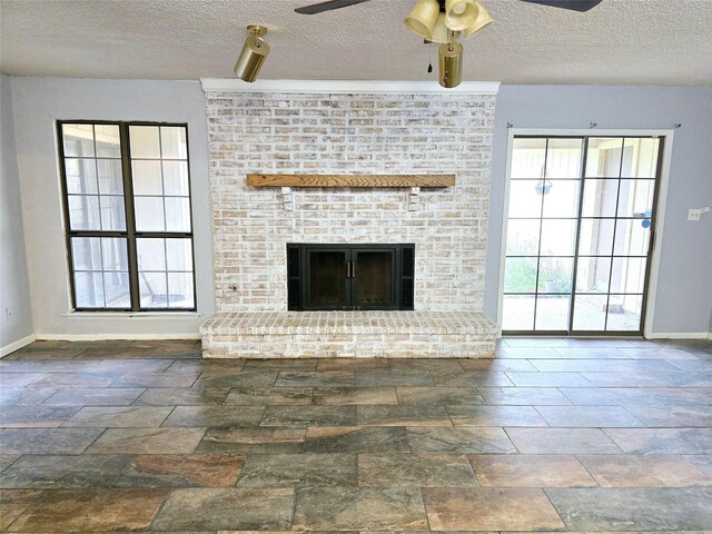 5000 Magnolia Ln, Bay City, TX 77414 - unfurnished living room featuring a textured ceiling, baseboards, a fireplace, ceiling fan, and stone finish flooring