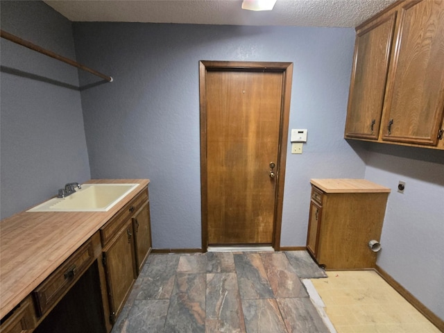 5000 Magnolia Ln, Bay City, TX 77414 - laundry room with electric dryer hookup, cabinet space, baseboards, a textured ceiling, and dark stone finish flooring