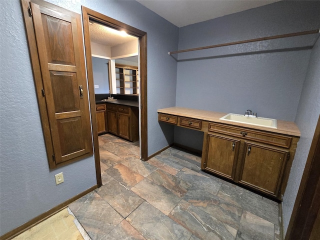 5000 Magnolia Ln, Bay City, TX 77414 - laundry room featuring a sink, baseboards, stone finish floors, a desk, and a textured wall
