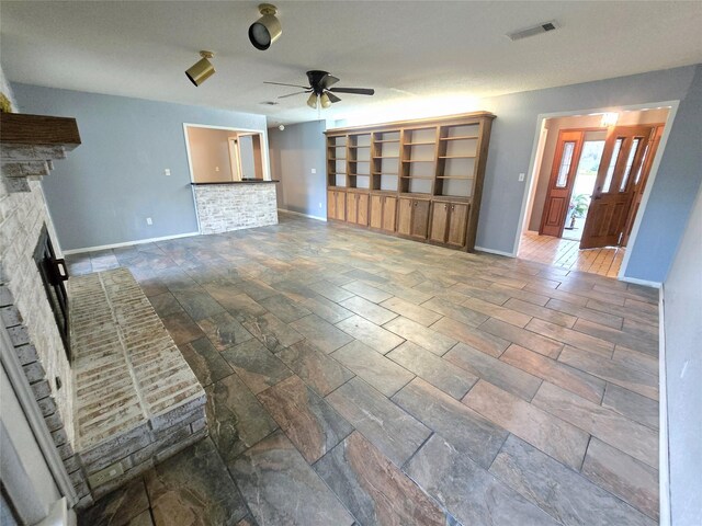 5000 Magnolia Ln, Bay City, TX 77414 - unfurnished living room with a ceiling fan, a fireplace with raised hearth, baseboards, and stone tile flooring