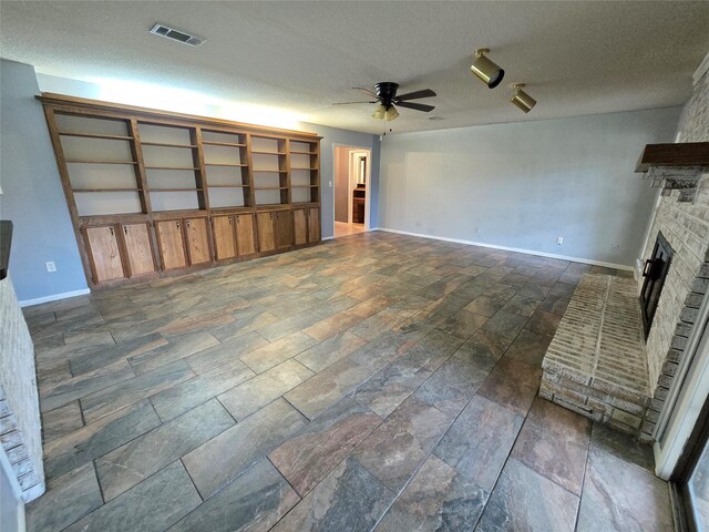 5000 Magnolia Ln, Bay City, TX 77414 - unfurnished living room featuring a ceiling fan, a fireplace, baseboards, a textured ceiling, and stone tile floors
