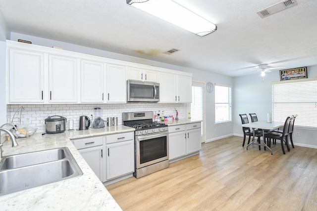 20418 Linden Tree Dr, Katy, TX 77449 - kitchen featuring appliances with stainless steel finishes, a sink, backsplash, light wood-style floors, and white cabinets