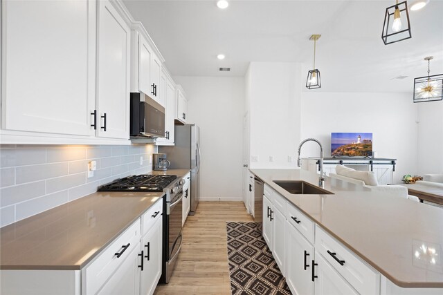 4234 Balboa Dr, Iowa Colony, TX 77583 - kitchen with appliances with stainless steel finishes, a sink, light wood finished floors, open floor plan, and tasteful backsplash