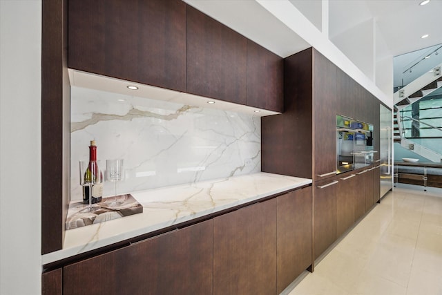 2110 Tangley St, Houston, TX 77005 - kitchen with decorative backsplash, modern cabinets, light stone counters, dark brown cabinets, and recessed lighting