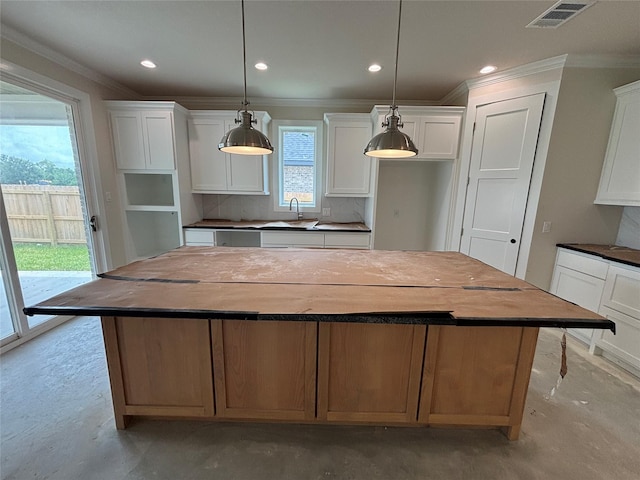 2804 Spector Dr, Bryan, TX 77808 - kitchen with ornamental molding, a kitchen island, concrete floors, a sink, and white cabinets