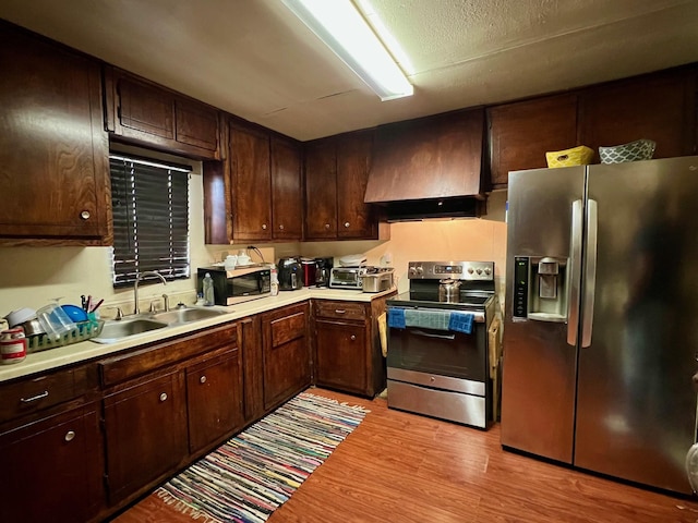 6301 Ezzard Charles Ln, Houston, TX 77091 - kitchen with stainless steel appliances, a sink, custom range hood, light wood-style flooring, and light countertops
