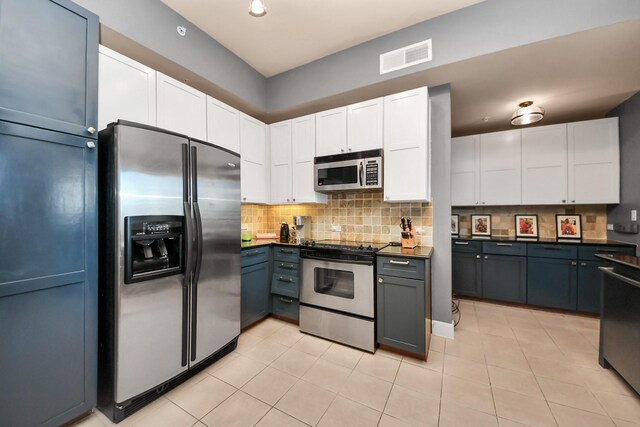 3333 Allen Pkwy Unit 1508, Houston, TX 77019 - kitchen with appliances with stainless steel finishes, decorative backsplash, white cabinetry, light tile patterned floors, and dark countertops