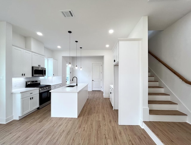 3109 Orange St, Houston, TX 77020 - kitchen featuring appliances with stainless steel finishes, a sink, light wood-style flooring, tasteful backsplash, and white cabinets