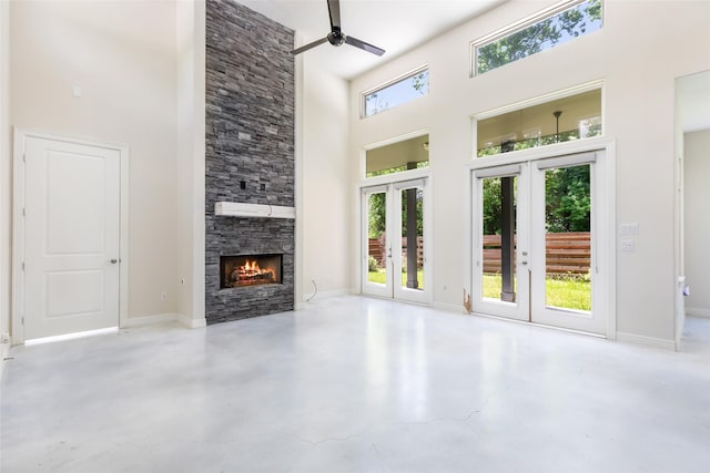 538 Magnolia Point Dr, Huffman, TX 77336 - unfurnished living room featuring french doors, a high ceiling, ceiling fan, concrete flooring, and a fireplace