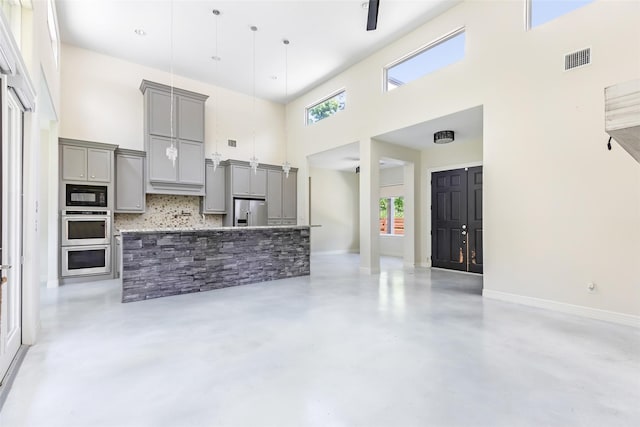 538 Magnolia Point Dr, Huffman, TX 77336 - kitchen featuring appliances with stainless steel finishes, gray cabinets, a high ceiling, backsplash, and finished concrete floors