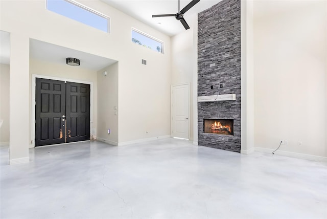 538 Magnolia Point Dr, Huffman, TX 77336 - unfurnished living room with a ceiling fan, a towering ceiling, finished concrete flooring, a fireplace, and baseboards