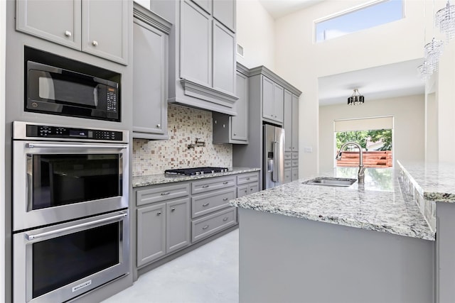 538 Magnolia Point Dr, Huffman, TX 77336 - kitchen featuring gray cabinets, appliances with stainless steel finishes, a sink, tasteful backsplash, and light stone countertops