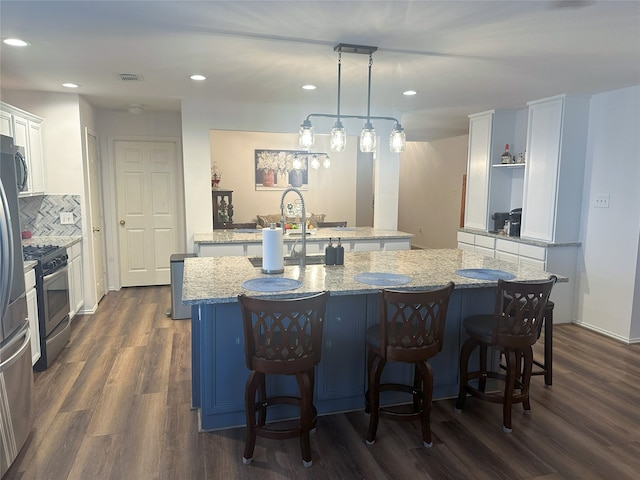 12107 English Brook Cir, Humble, TX 77346 - kitchen featuring a kitchen island with sink, stainless steel range with gas stovetop, white cabinetry, a kitchen bar, and recessed lighting