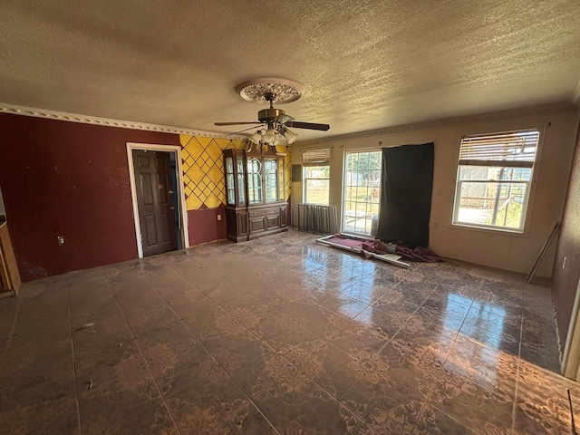 1205 14th St, Seagraves, TX 79359 - spare room featuring a textured ceiling, a ceiling fan, and wallpapered walls