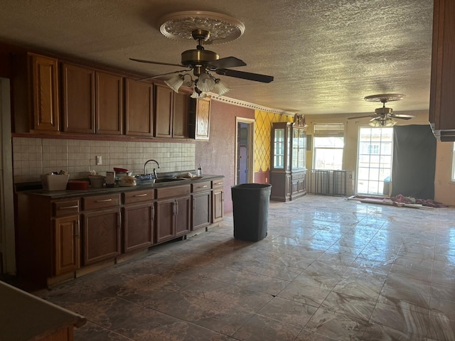1205 14th St, Seagraves, TX 79359 - kitchen with a ceiling fan, a sink, dark countertops, a textured ceiling, and decorative backsplash