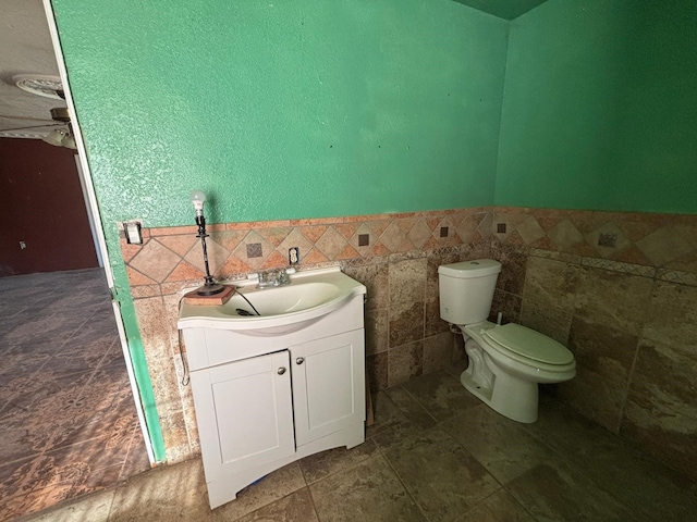 1205 14th St, Seagraves, TX 79359 - half bath with vanity, tile walls, toilet, wainscoting, and ceiling fan