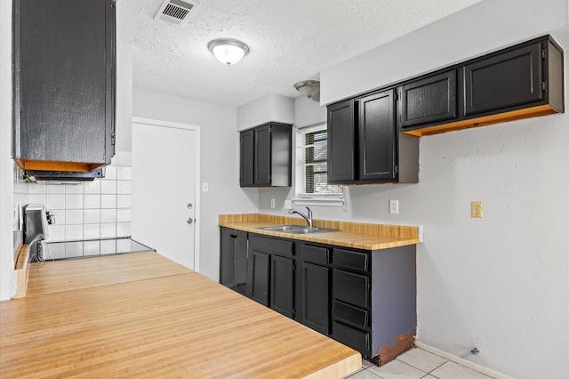 9918 Enchanted Stone Dr, Houston, TX 77070 - kitchen featuring light countertops, dark cabinets, a sink, a textured ceiling, and tasteful backsplash