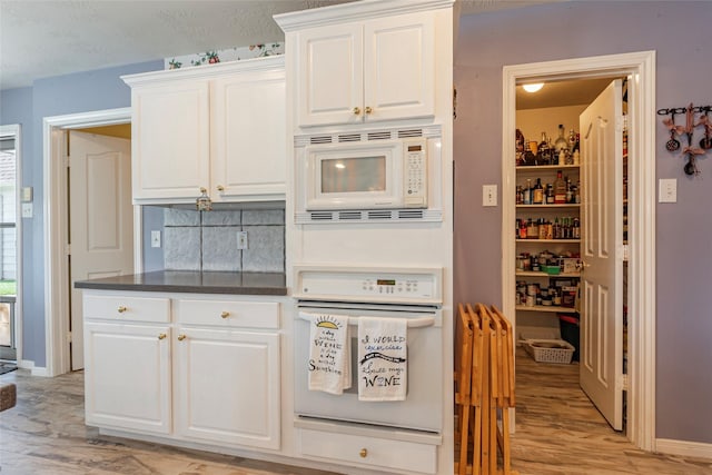 811 Hackberry Ln, Friendswood, TX 77546 - kitchen featuring white appliances, light wood-style flooring, white cabinetry, tasteful backsplash, and baseboards