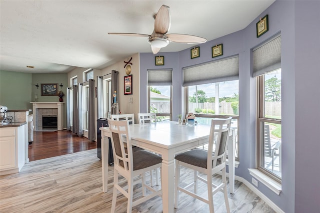 811 Hackberry Ln, Friendswood, TX 77546 - dining area featuring ceiling fan, light wood-style floors, a tile fireplace, and baseboards