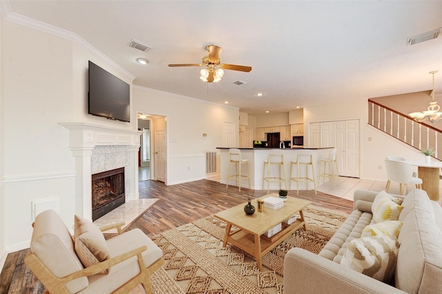 14823 Atterbury Dr, Sugar Land, TX 77498 - living area featuring wood finished floors, a ceiling fan, a chandelier, a fireplace, and ornamental molding