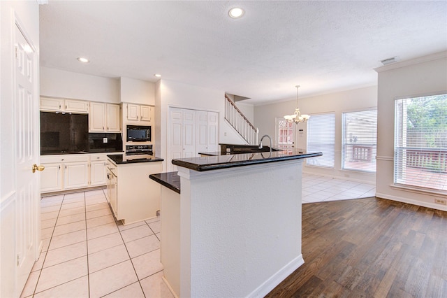14823 Atterbury Dr, Sugar Land, TX 77498 - kitchen with a kitchen island with sink, black appliances, a chandelier, dark countertops, and recessed lighting