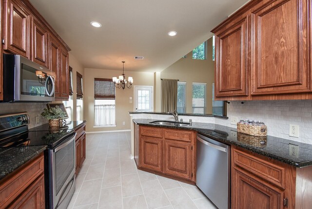 2803 Lakecrest Way Dr, Katy, TX 77493 - kitchen with appliances with stainless steel finishes, a sink, light tile patterned flooring, backsplash, and a peninsula
