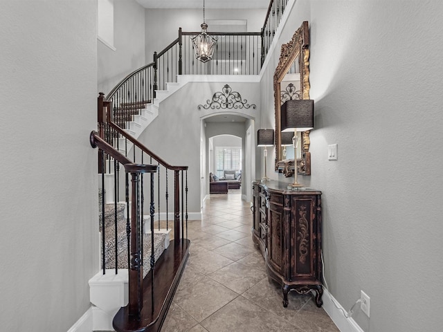 12118 Pinelands Park Ln, Humble, TX 77346 - tiled foyer entrance featuring stairs, arched walkways, a chandelier, a textured wall, and a towering ceiling