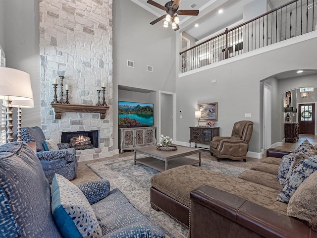 12118 Pinelands Park Ln, Humble, TX 77346 - living room featuring ceiling fan, a stone fireplace, arched walkways, and a towering ceiling