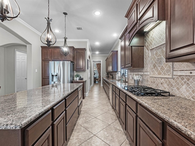 12118 Pinelands Park Ln, Humble, TX 77346 - kitchen with black gas stovetop, stainless steel fridge with ice dispenser, crown molding, backsplash, and dark brown cabinetry