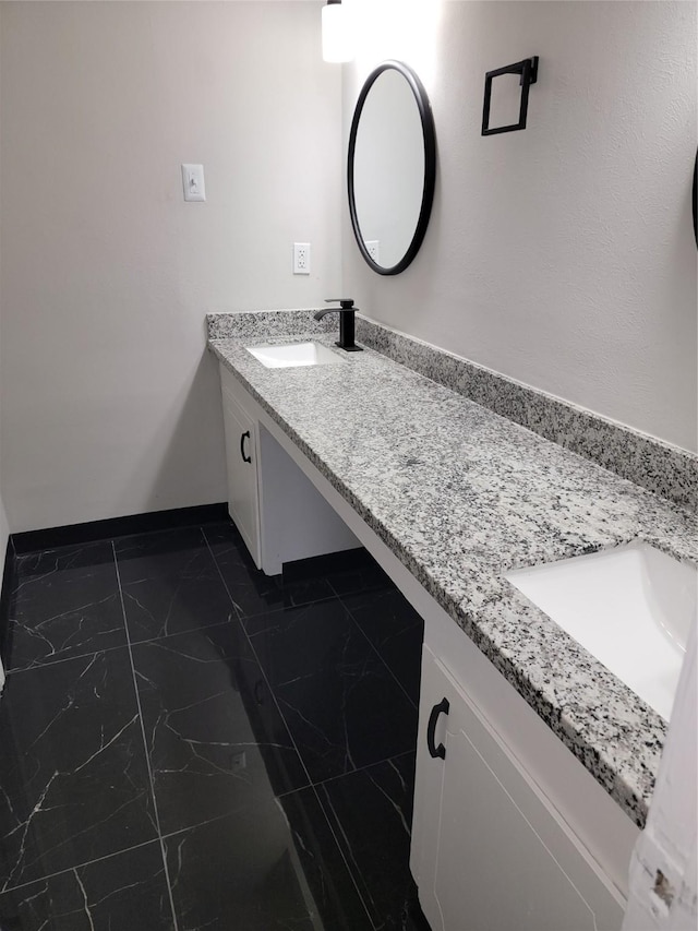 5814 Fontenelle Dr, Houston, TX 77035 - bathroom featuring double vanity, marble look tile flooring, and baseboards