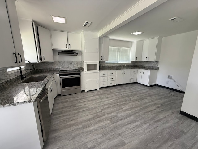 5814 Fontenelle Dr, Houston, TX 77035 - kitchen featuring appliances with stainless steel finishes, white cabinets, tasteful backsplash, under cabinet range hood, and wood finished floors