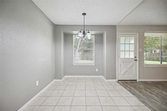 2311 N Spring Dr, Spring, TX 77373 - unfurnished dining area featuring a textured ceiling, a chandelier, baseboards, and light tile patterned floors