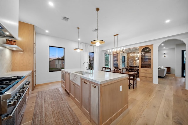 3111 Eastman St, Houston, TX 77022 - kitchen featuring a sink, light brown cabinetry, light wood-style flooring, a center island with sink, and arched walkways