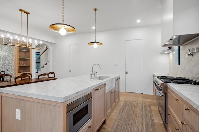 3111 Eastman St, Houston, TX 77022 - kitchen with stainless steel appliances, a sink, wall chimney range hood, light wood-style flooring, and a center island with sink