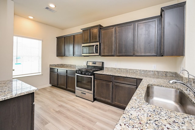 405 Elaine Valley Dr Unit D, Katy, TX 77493 - kitchen with appliances with stainless steel finishes, a sink, dark brown cabinets, light wood-type flooring, and recessed lighting