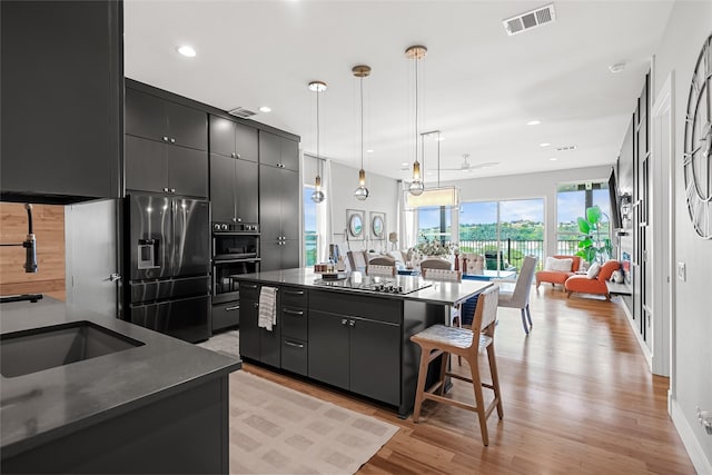 20107 Continental Dr Unit A, Lago Vista, TX 78645 - kitchen featuring dark countertops, dark cabinetry, a kitchen island, black appliances, and light wood-style flooring